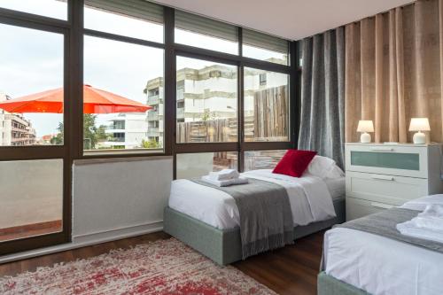 a bedroom with two beds and a large window at Cascais Sun Terrace Casino Estoril Apartment in Estoril