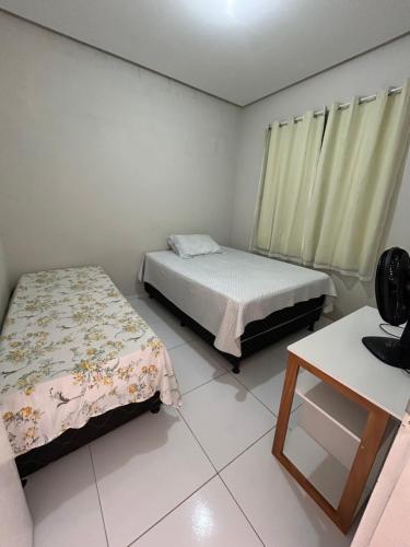 ein Zimmer mit zwei Betten und einem Tisch darin in der Unterkunft Casa aconchego in Canindé de São Francisco