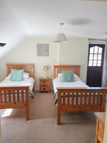 a bedroom with two beds and a table with a lamp at The Crown Hotel in Corwen