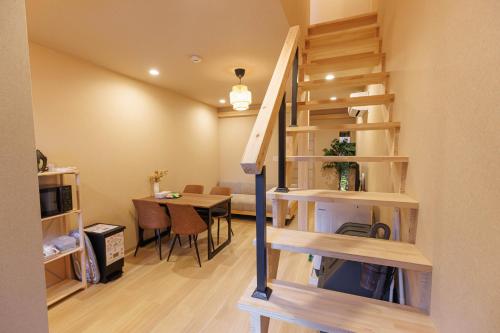 a room with a staircase and a dining room with a table at 秋桜上本町 in Osaka