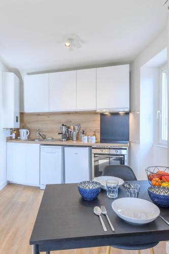 une cuisine avec des armoires blanches et une table dans l'établissement Le cœur des Alpes, à Grenoble
