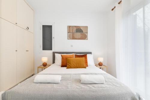 a white bedroom with a large bed with orange pillows at Limnaria Gardens SUPERB VILLA by VICHY Holidays in Paphos