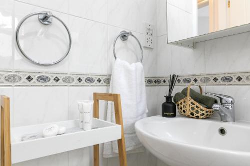 a white bathroom with a sink and a mirror at Limnaria Gardens SUPERB VILLA by VICHY Holidays in Paphos