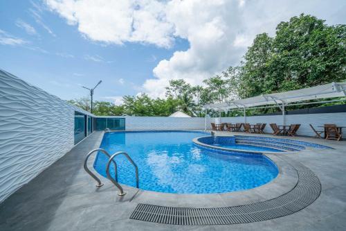a swimming pool with tables and chairs next to a building at KYRIAD M2 LAMPUNG in Lampung