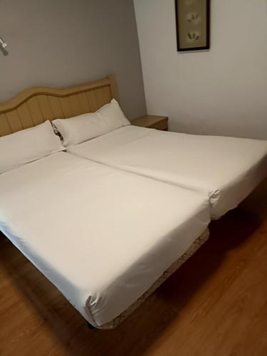 a bed with white sheets and pillows in a room at Hotel Mercado by gaiarooms in Salamanca
