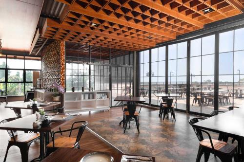 a restaurant with tables and chairs and large windows at KYRIAD M2 LAMPUNG in Lampung