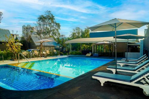 a large swimming pool with chairs and umbrellas at Luna Hut Resort in Hua Hin