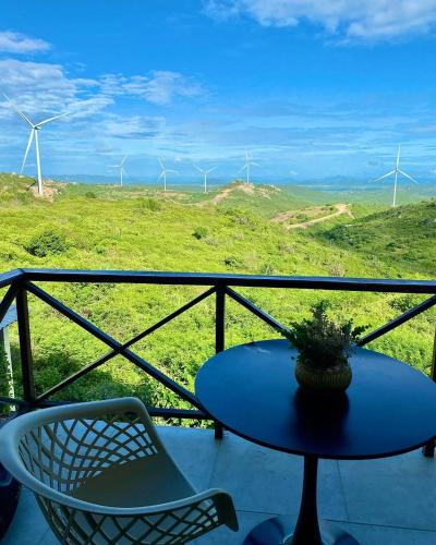 a table and chairs on a balcony with wind turbines at Varandas do Vale Chalé in Monte das Gameleiras