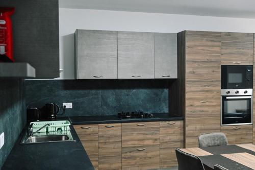 a kitchen with wooden cabinets and a black counter top at Cerviola Luxury 3 bedroom Apartments in Il-Ħamrija