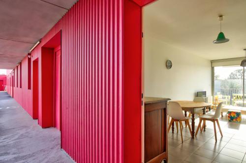 a red wall in a room with a table and chairs at Le George Sand parking privé in Blagnac