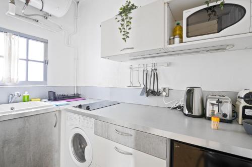 - une cuisine blanche avec un lave-linge et un évier dans l'établissement Superb Apartment Quartier Les Marais Free Netflix, à Paris