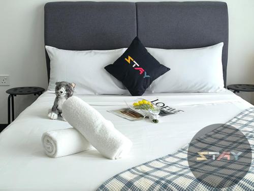 a dog sitting on top of a white bed at Almas Couple Urban Retreat Puteri Harbour BySTAY in Iskandar Puteri