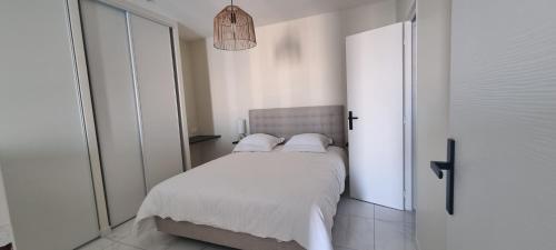 une chambre avec un lit avec des draps blancs et des oreillers dans l'établissement Le Môle, à Sète