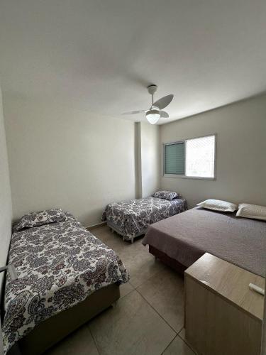 a bedroom with two beds and a ceiling fan at Apartamento completo no Centro- Mongaguá Pé na areia in Mongaguá