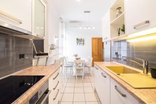 a kitchen with white cabinets and a table with chairs at Golden Star Apartment - Spacious City Center Stay in Zagreb