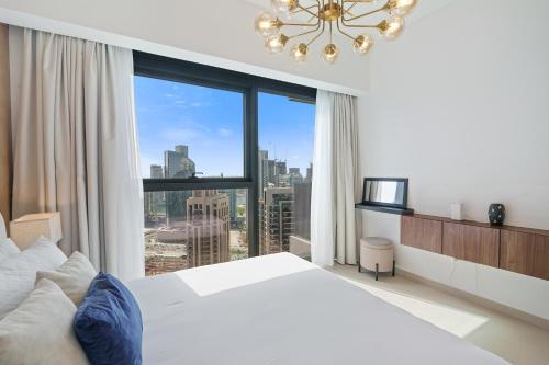 a white bedroom with a large window with a view at Stylish 1 Br In Downtown Near Burj Khalifa in Dubai