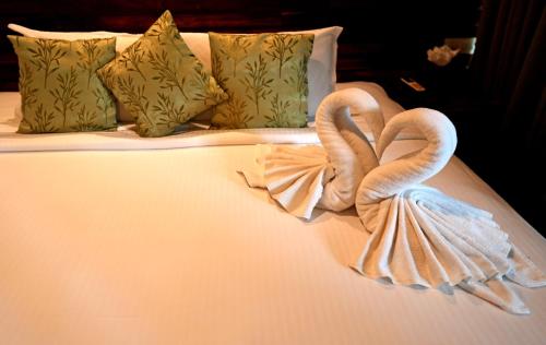 two towel swans are made to look like they are on a bed at Wayanad Silverwoods Forest Resort & Spa in Padinjarathara