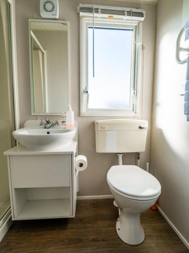 a bathroom with a toilet and a sink and a window at North Shore Skegness, 3 Bedroom 2 Bathroom Sleeps 8 in Skegness
