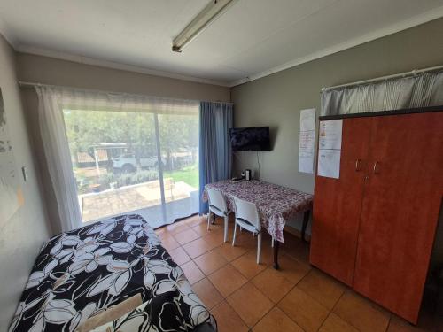 a bedroom with a bed and a table and a window at Woodhills Guest house in Piet Retief