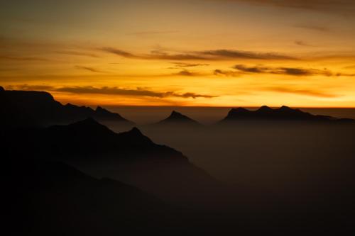 a sunset over the mountains in the horizon at The Farside Munnar in Suryanelli