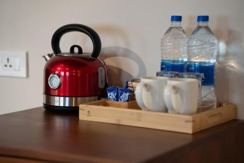 a tea kettle and cups on a table with water bottles at The Farside Munnar in Suryanelli