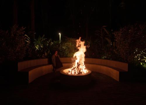 a woman standing next to a fire fountain at night at The Farside Munnar in Suryanelli