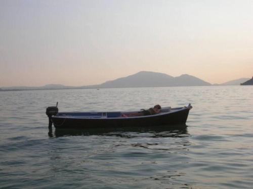 a man is sitting in a boat in the water at la casa dell'uva in Monte Isola