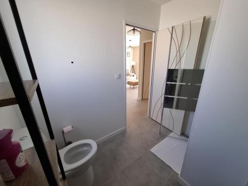 La salle de bains est pourvue de toilettes et d'une porte de douche en verre. dans l'établissement Appartement 5B - Saintes, à Saintes