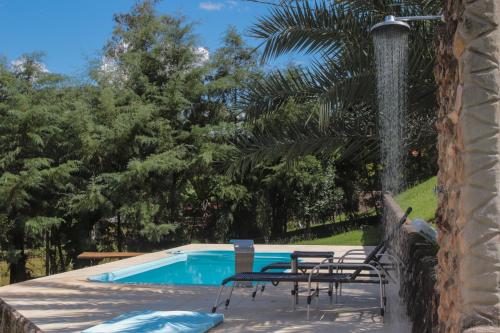 a swimming pool with chairs and a water fountain at Chácara Águas Claras in Monte Sião