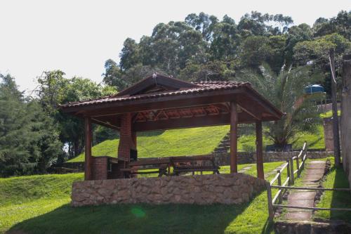 a wooden pavilion with a bench in a park at Chácara Águas Claras in Monte Sião