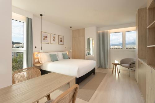a hotel room with a bed and a desk and a table at Staybridge Suites & Apartments Malaga by IHG in Málaga