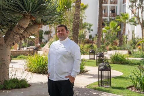 a man in a white shirt standing next to a bird cage at The View Agadir in Agadir