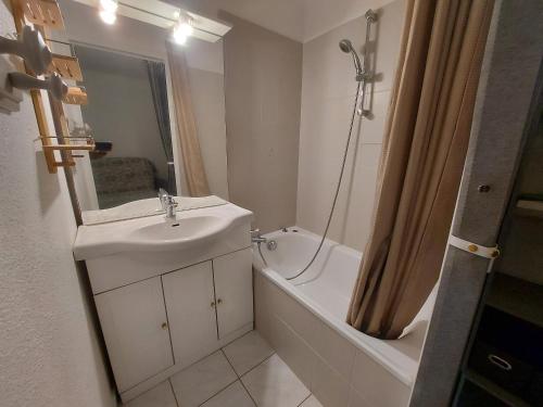 La salle de bains blanche est pourvue d'un lavabo, d'une baignoire et d'une douche. dans l'établissement Appartement RDC avec Terrasse, Parking et Animaux Acceptés à 100m de la Plage - FR-1-776-116, à Saint-Cyprien
