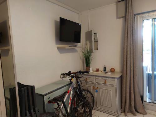 - un vélo garé dans une pièce avec une télévision murale dans l'établissement Appartement RDC avec Terrasse, Parking et Animaux Acceptés à 100m de la Plage - FR-1-776-116, à Saint-Cyprien