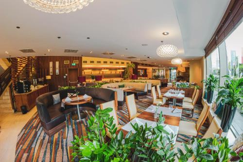 a restaurant with couches and tables and plants at Hilton Garden Inn Rzeszów in Rzeszów