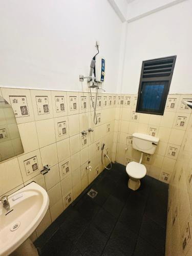a bathroom with a toilet and a sink at Hotel Sunil's in Kataragama