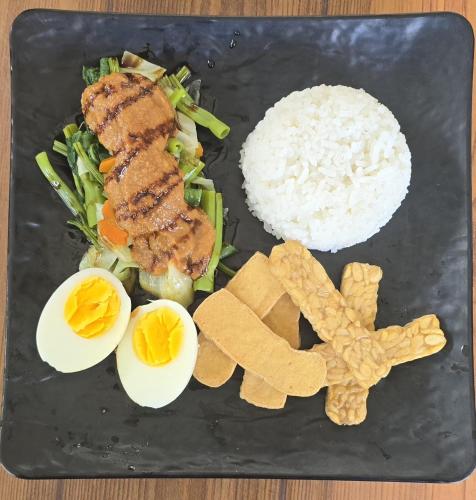 a plate of food with eggs rice and vegetables at Makarma Resort Lombok in Senggigi 