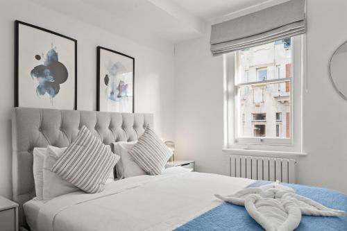 Un dormitorio blanco con una cama grande con una manta azul. en Prime Central London Residences, en Londres