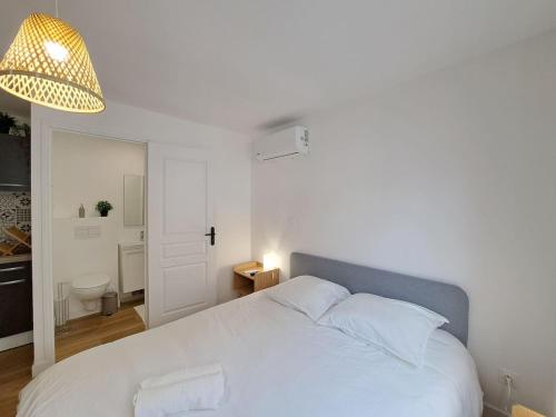 - une chambre avec un lit blanc et une lampe éclairée dans l'établissement Naples - Studio centre-ville, à Reims