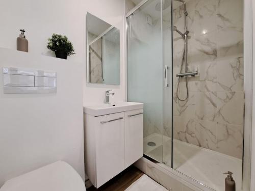 une salle de bain blanche avec une douche et un lavabo dans l'établissement Naples - Studio centre-ville, à Reims