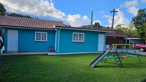 a playground in front of a blue house at Da Matta House Estilo e Conforto a 8km de Capivari in Campos do Jordão
