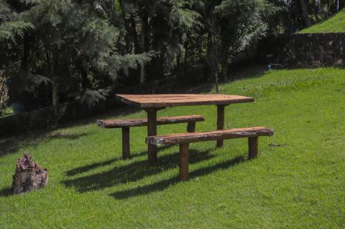 a picnic table and two benches in the grass at Chácara Águas Claras in Monte Sião
