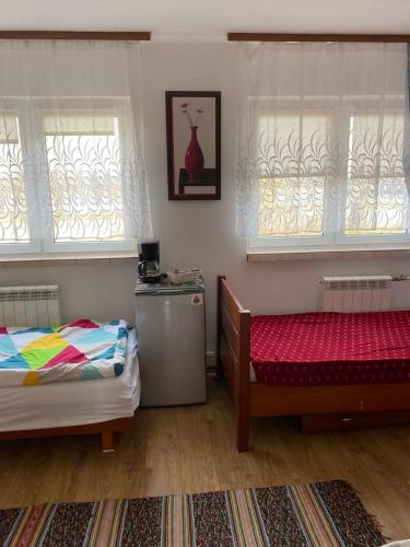 a bedroom with two beds and a table and two windows at Pokoje przy Tamie in Włocławek