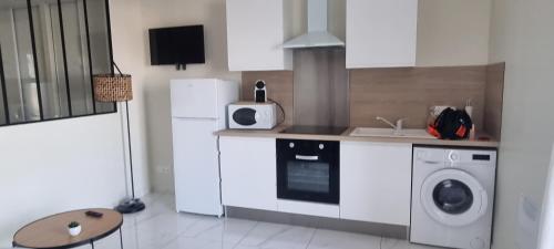 une cuisine avec des armoires blanches et une laveuse et une sécheuse dans l'établissement Le Phare, à Sète