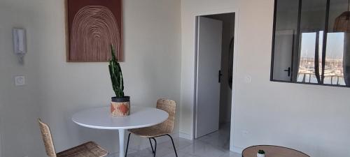 une table et des chaises blanches dans une pièce avec une plante dans l'établissement Le Phare, à Sète