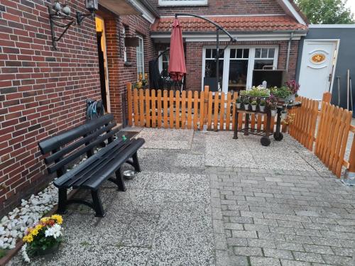 a bench in front of a house with a fence at Hotel-Pension Friesenruh in Bensersiel