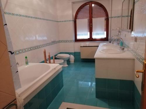 a bathroom with two sinks and a tub and two toilets at L'Ambra in Alghero