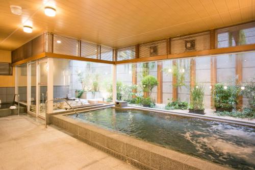 a swimming pool in a building with a large window at Nishitetsu Hotel Croom Hakata in Fukuoka
