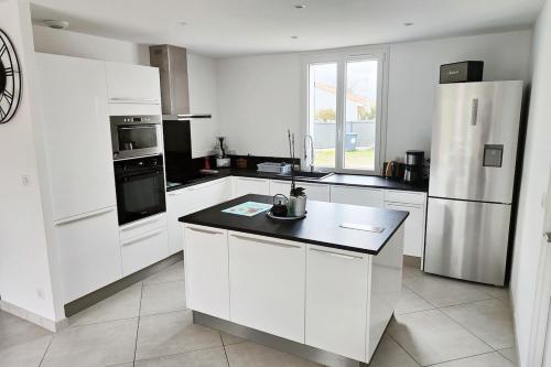 une cuisine blanche avec des armoires blanches et un réfrigérateur dans l'établissement Maison MANGUELI - Bassin d 'Arcachon, à Audenge