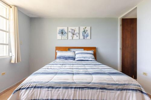 a bedroom with a bed with a blue and white comforter at Sunrise in Villas del Faro in Emajagua